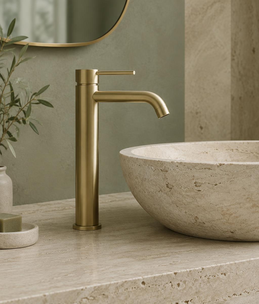 Brushed brass basin mixer and carved stone vessel basin on pale travertine